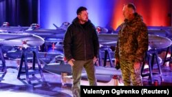 Президент Украины Владимир Зеленский и главком ВСУ Александр Сырский на фоне экспозиции украинских ударных дронов. Декабрь 2024 года
