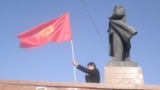 A man waves a Kyrgyz flag next to a statue of Soviet leader Vladimir Lenin in central Osh. City authorities took down the statue in June.