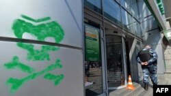 Un polițist păzește sediul băncii rusesti Sberbank, in Kiev, pe care a fost pictat de activiști ucraineni simbolul numit "omuleți verde", care ii desemnează pe pro-rușii si separatiștii ce activează in Ucraina.