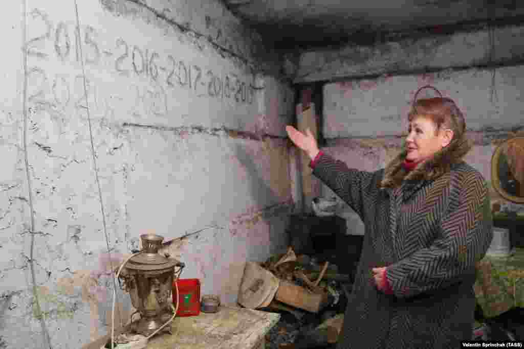 Ясиноватая қаласындағы бомбадан жасырынатын орынның ішкі қабырғасындағы жазуларды көрсетіп тұрған әйел. Қабырғада Жаңа жылды осы жерде қарсы алған адамдардың жазғаны да бар. Донецк облысы, 24 наурыз 2021 жыл.